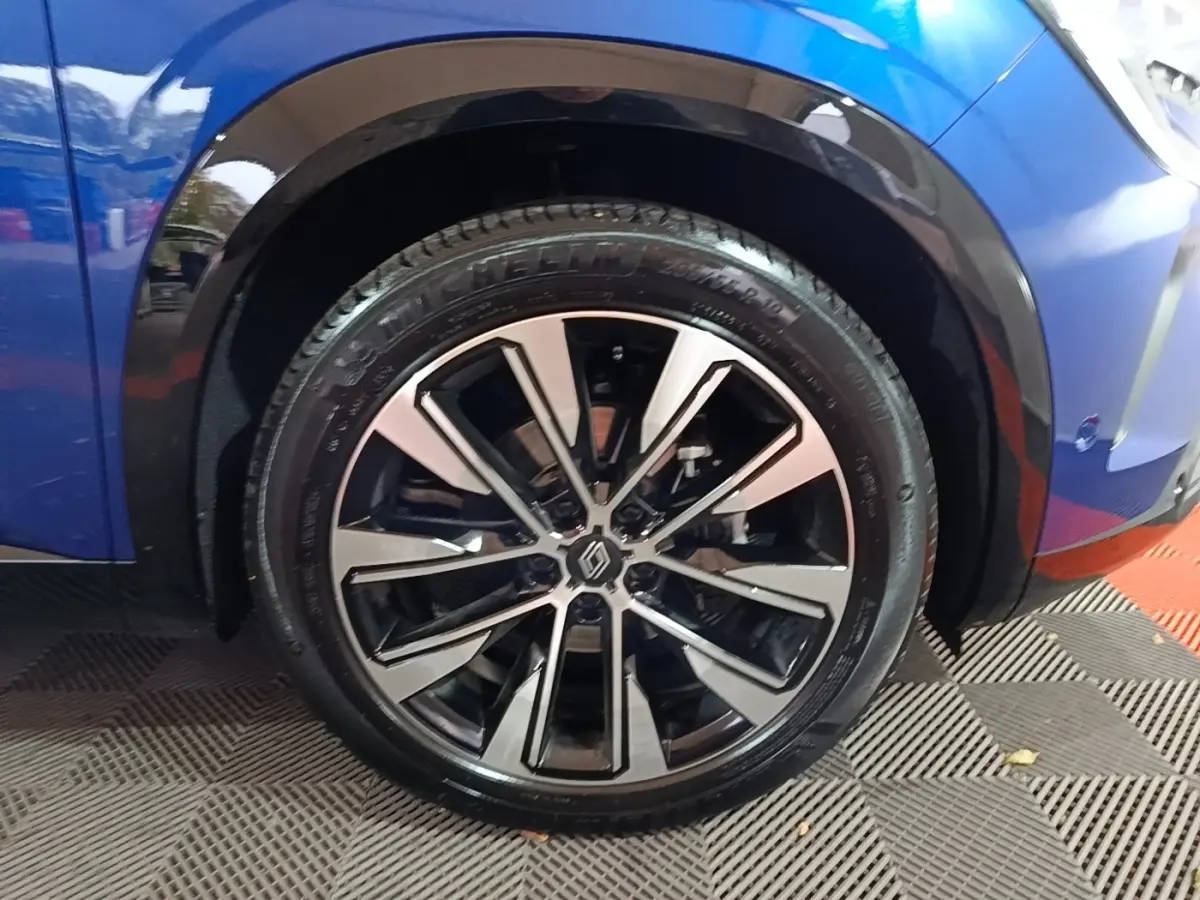 Gros plan sur la roue avant droite d’un Renault Austral bleu 2024 avec jante alliage bicolore moderne.