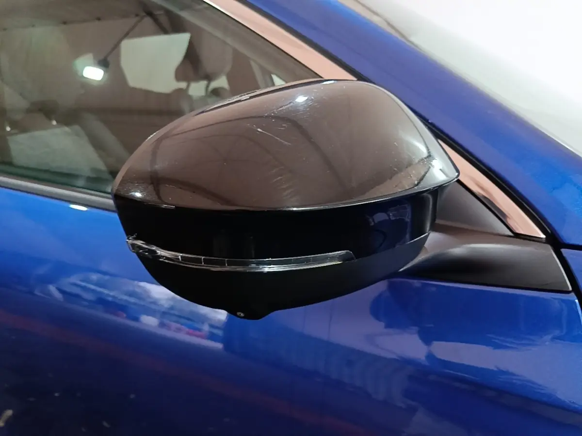 Rétroviseur noir en gros plan côté gauche d’un Renault Austral bleu 2024, avec clignotant intégré.