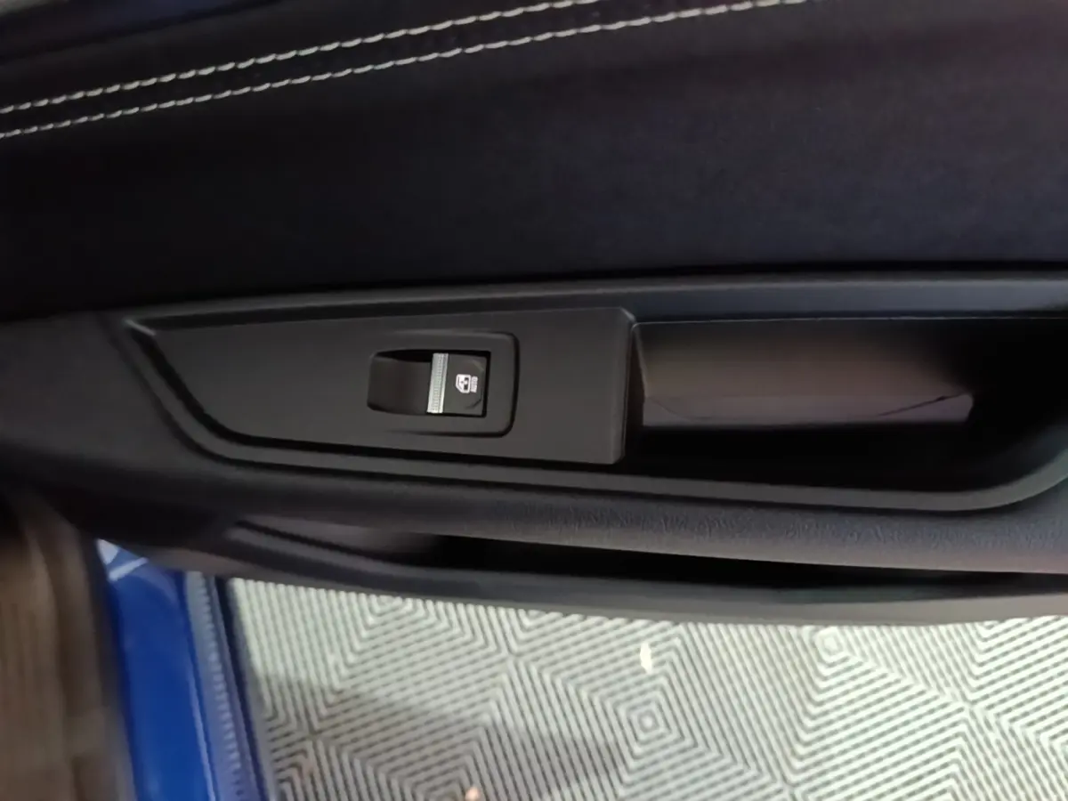 Détail de la commande de verrouillage électrique sur la porte intérieure côté gauche d’un Renault Austral bleu 2024.