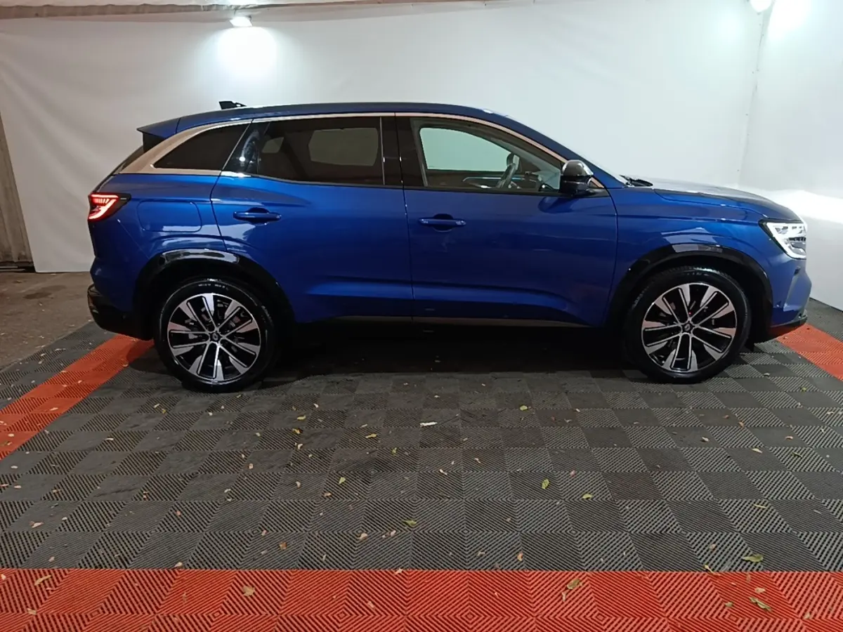 Profil droit du Renault Austral bleu 2024 avec jantes alliage et toit noir contrasté dans un studio.