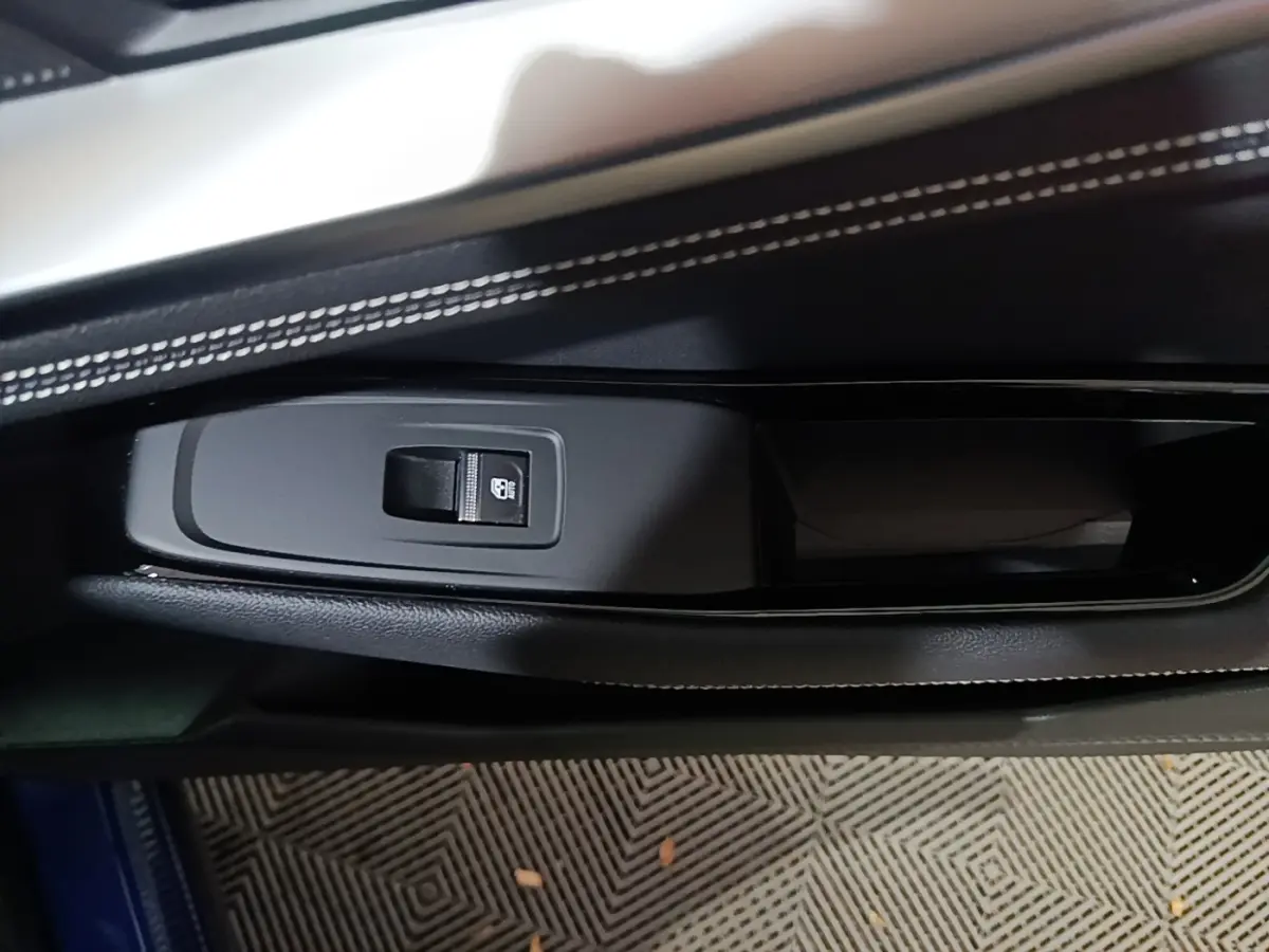 Détail de la commande de verrouillage sur la porte côté gauche du Renault Austral bleu, avec surpiqûres blanches visibles.