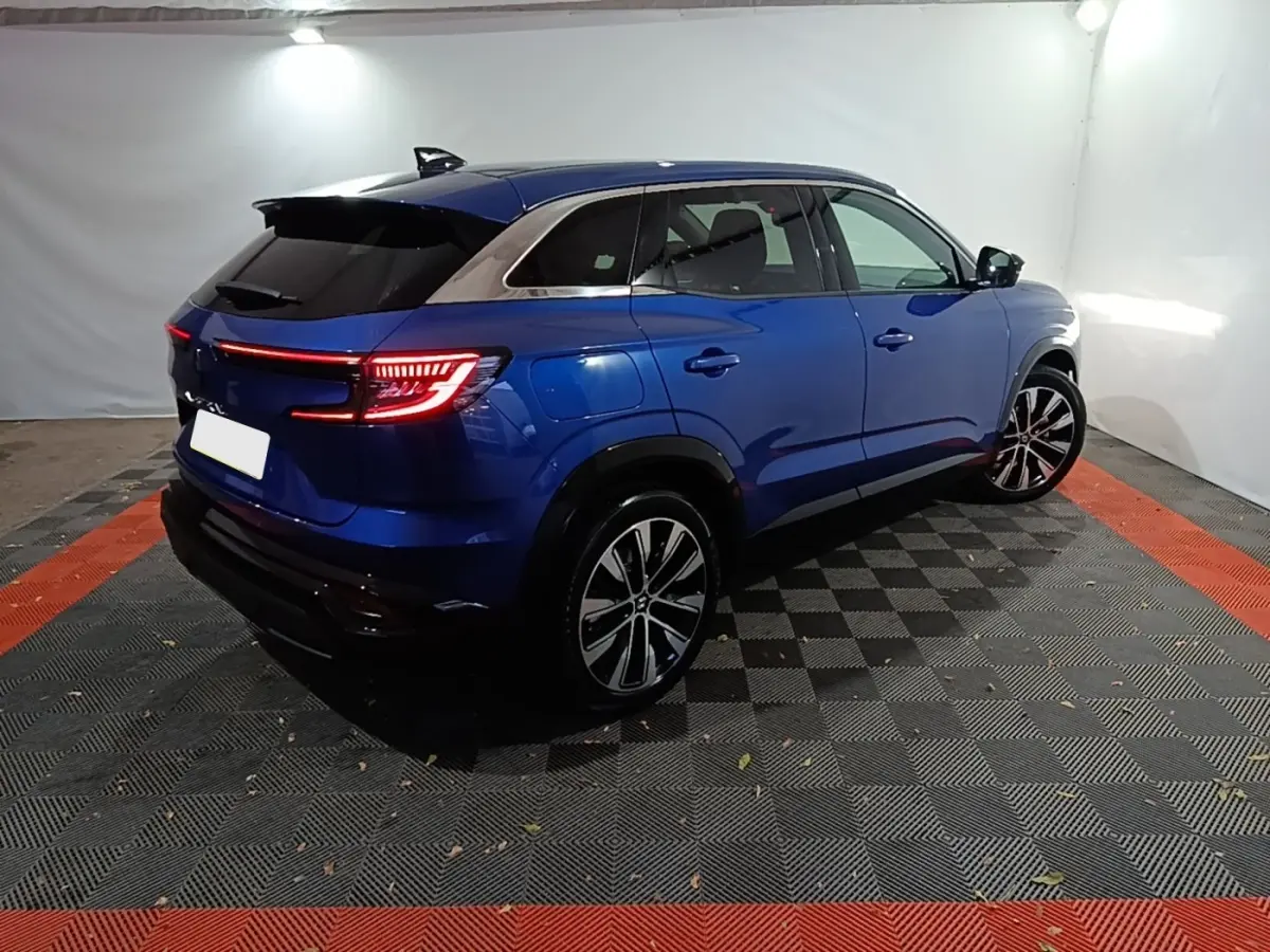 Renault Austral bleu en vue 3/4 arrière droit, feux LED allumés et jantes alliage distinctives.