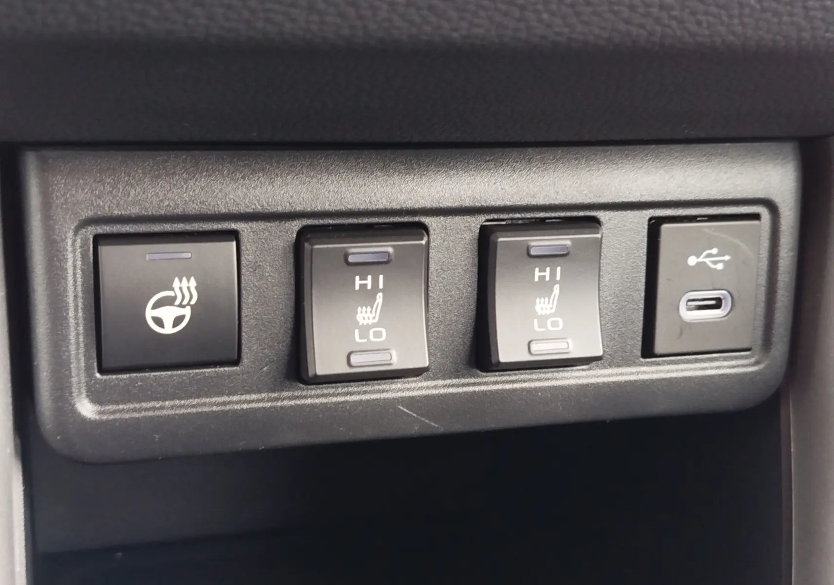 Gros plan sur les commandes de chauffage de volant et sièges avec port USB dans le Toyota Corolla Cross gris acier 2025.