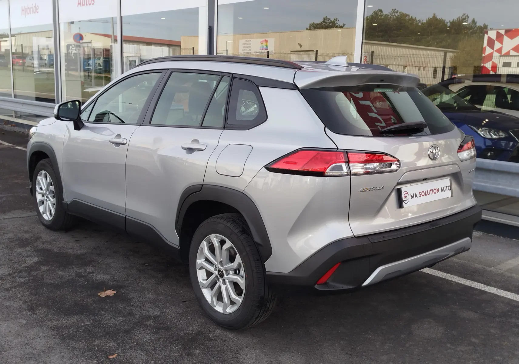 Vue 3/4 arrière droite d'un Toyota Corolla Cross gris acier 2025, avec jantes alliage et feux arrière LED distinctifs.