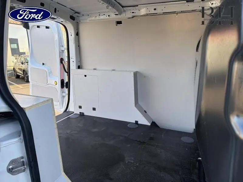 Vue intérieure arrière du Ford Transit Connect blanc glacier, montrant l’espace de chargement avec cloison pleine et plancher caoutchouc.