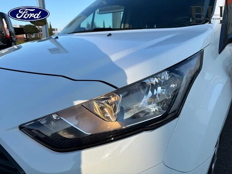 Gros plan sur le phare avant droit du Ford Transit Connect blanc glacier, mettant en valeur son design moderne et anguleux.