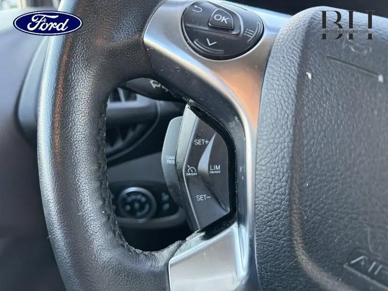 Gros plan sur le volant multifonction noir du Ford Transit Connect, avec commandes de régulateur de vitesse visibles.