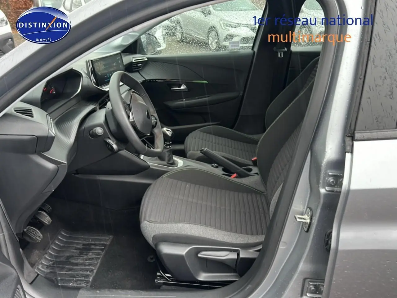 Vue intérieure côté conducteur de la Peugeot 208 1.2 PureTech 100 Active gris Artense avec sièges tissu noir/gris.