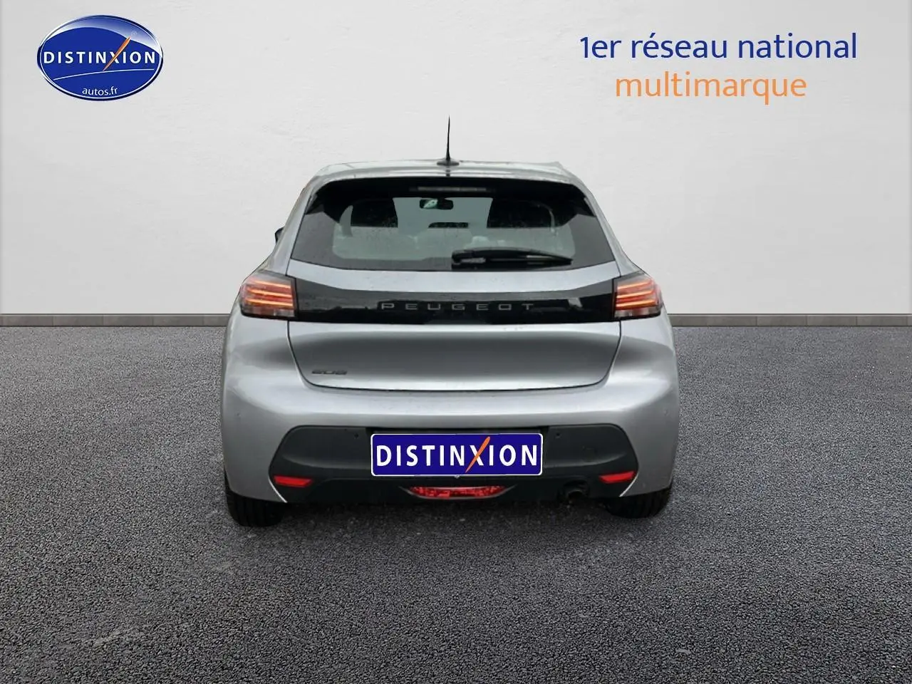 Vue arrière d'une Peugeot 208 1.2 PureTech 100 Active gris Artense avec feux arrière allumés sur fond neutre.