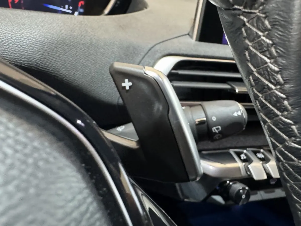 Gros plan sur la palette de changement de vitesses + au volant cuir noir du Peugeot 3008 orange, version PureTech 130.