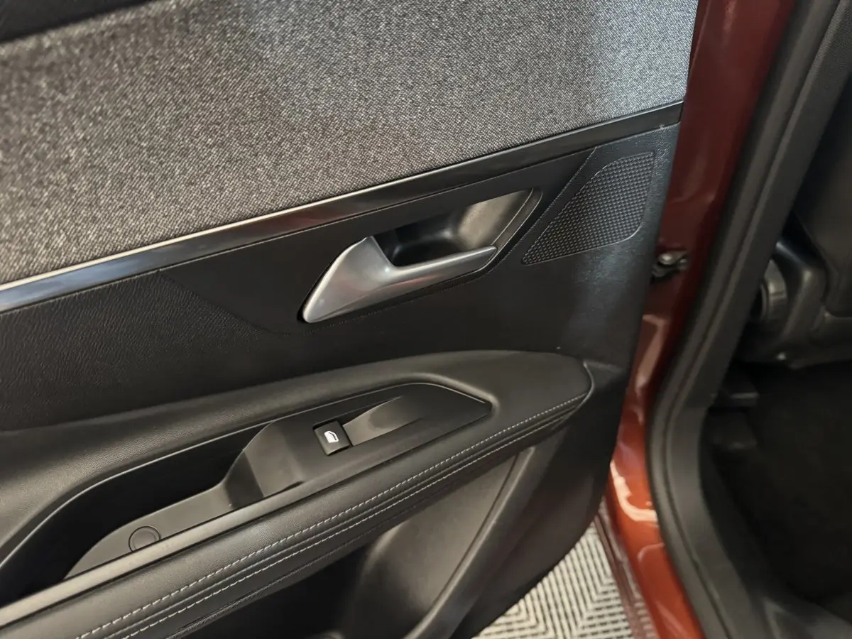 Gros plan sur la porte arrière gauche noire avec poignée argentée et partie extérieure orange du Peugeot 3008 2020.