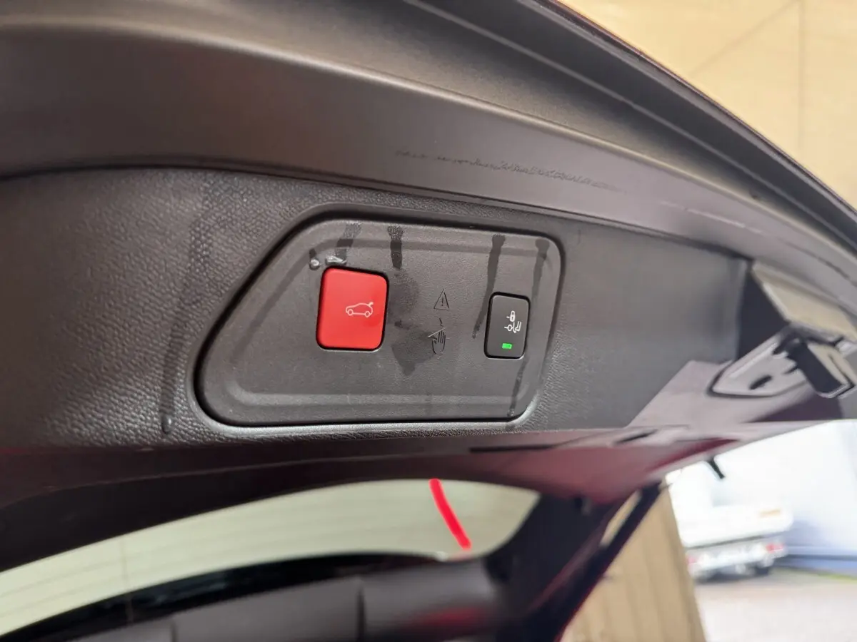 Gros plan sur les boutons d'ouverture et fermeture électrique du coffre du Peugeot 3008 orange, vue intérieure arrière.