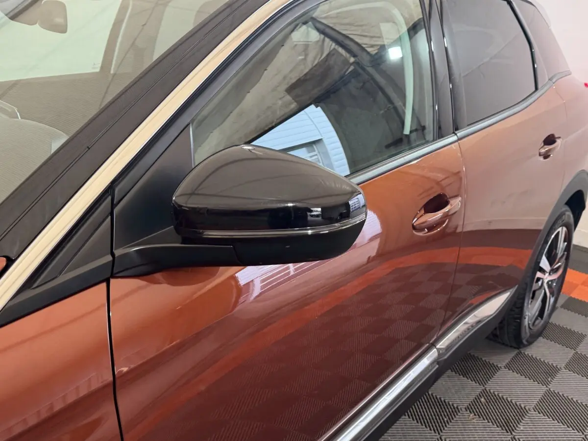 Vue latérale droite rapprochée du Peugeot 3008 orange, mettant en valeur le rétroviseur noir brillant et la poignée de porte.