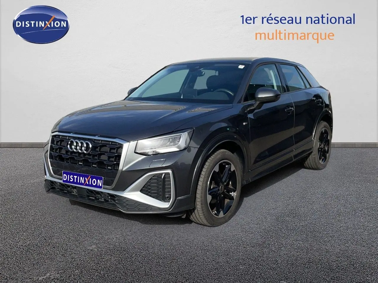 Audi Q2 gris Manhattan métal en 3/4 avant droit, avec calandre noire et jantes noires distinctives.