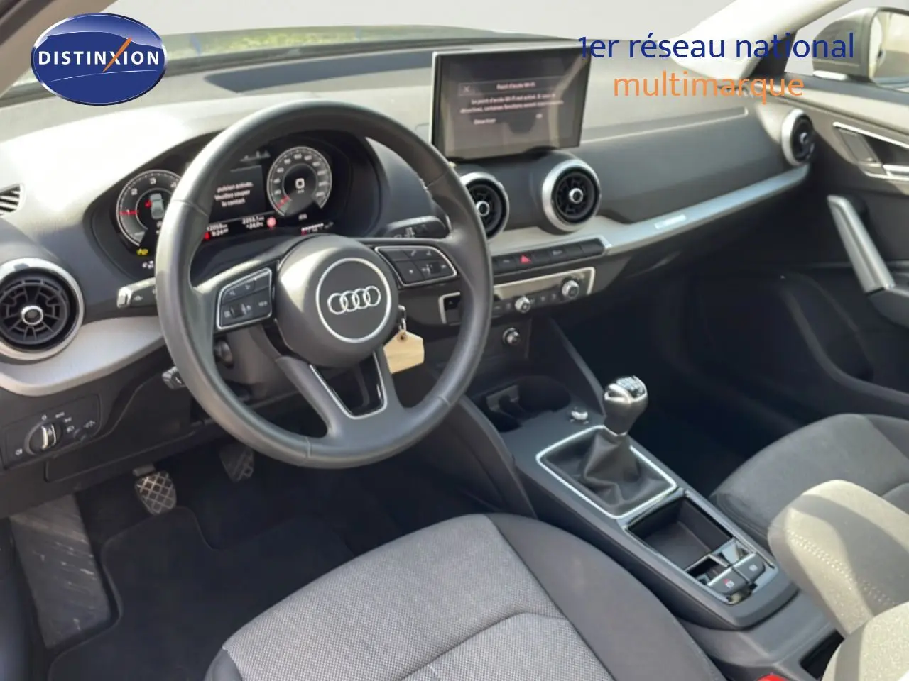 Vue intérieure de l'Audi Q2 30 TDI S-Line 2025 montrant le volant, tableau de bord numérique et levier de vitesse manuel.