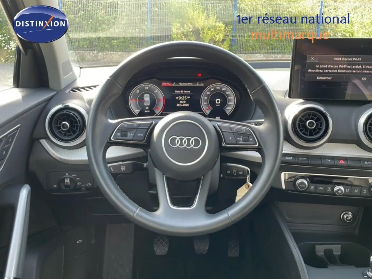 Vue frontale de l'intérieur de l'Audi Q2 30 TDI S-Line 2025, volant cuir noir et tableau de bord digital.