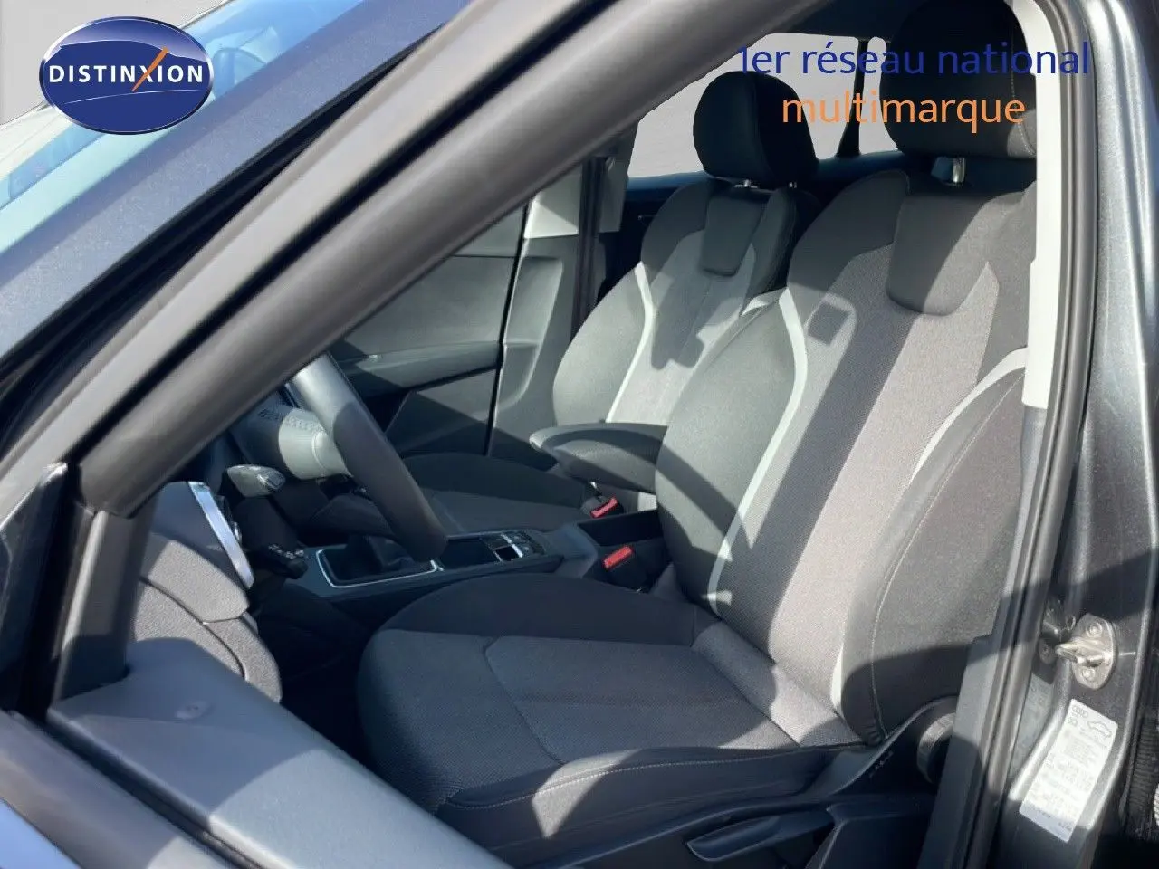 Vue intérieure côté conducteur de l'Audi Q2 30 TDI S-Line 2025 avec sièges tissu gris et volant cuir multifonction.