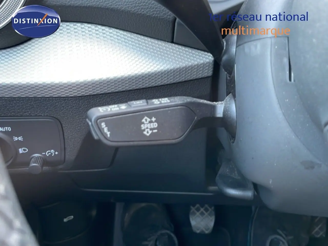Détail intérieur montrant le levier de régulateur de vitesse et la commande d'éclairage sur un Audi Q2 gris Manhattan.