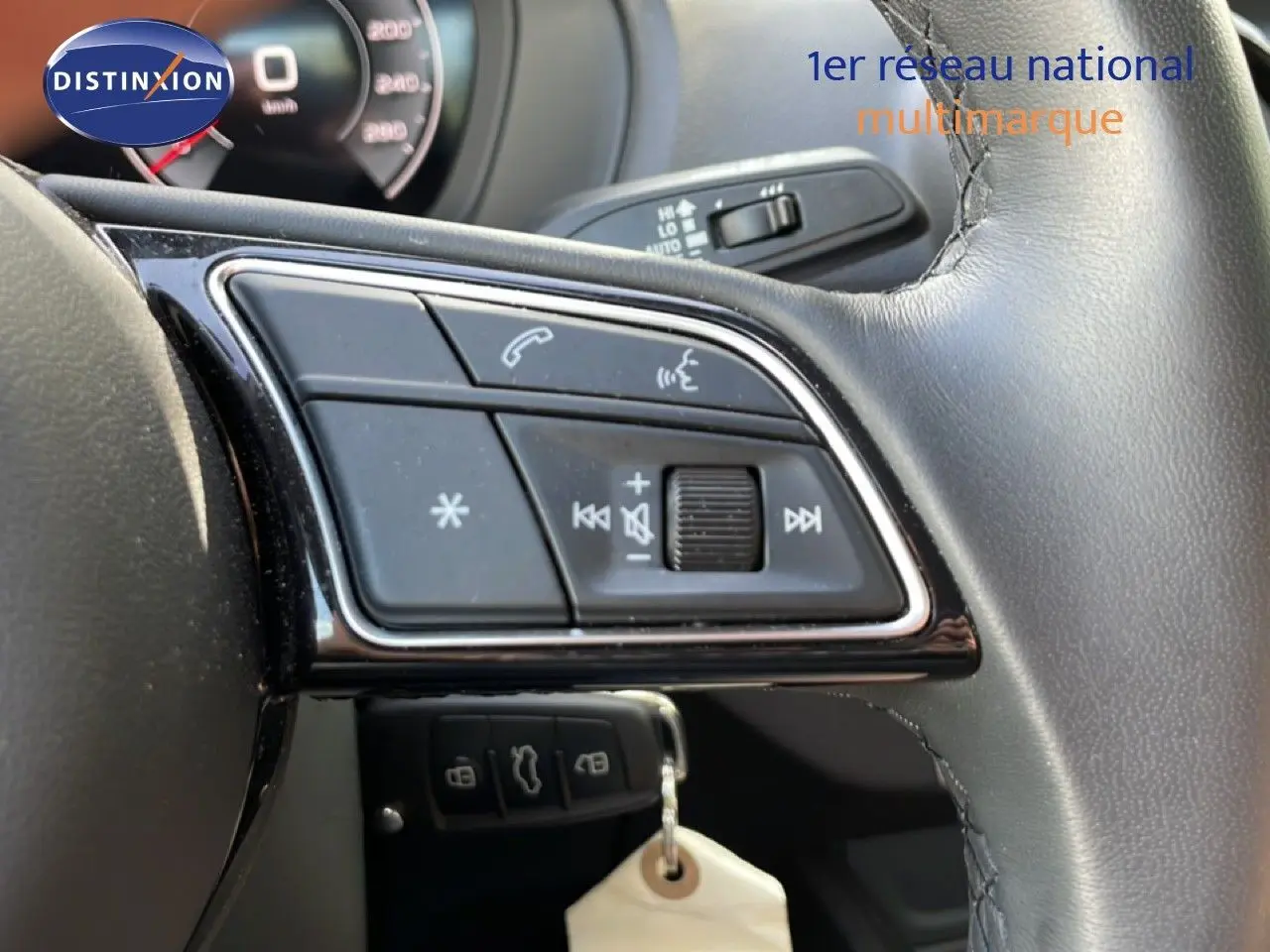 Gros plan sur les commandes au volant en cuir noir de l'Audi Q2 30 TDI S-Line, avec tableau de bord partiellement visible.
