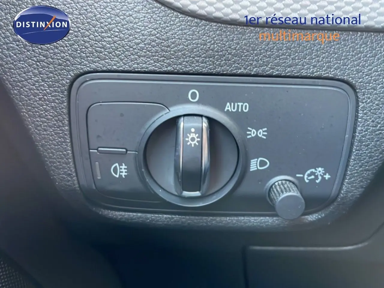 Gros plan sur le bouton de commande des phares de l'Audi Q2 30 TDI S-Line, intérieur noir texturé.
