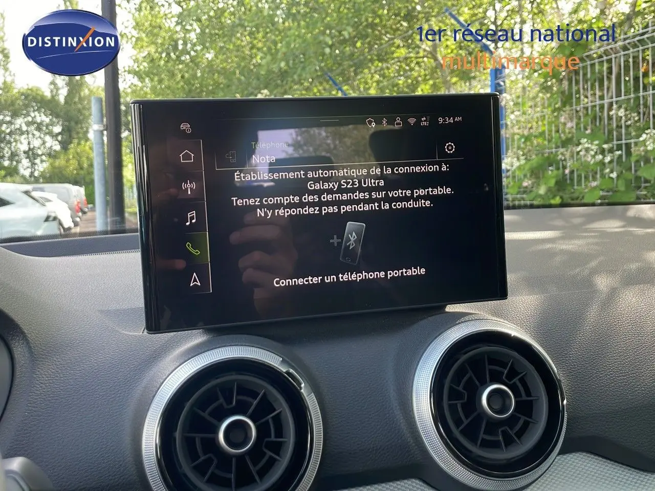 Écran tactile central affichant la connexion Bluetooth, avec deux aérateurs ronds argentés sur un tableau de bord noir.