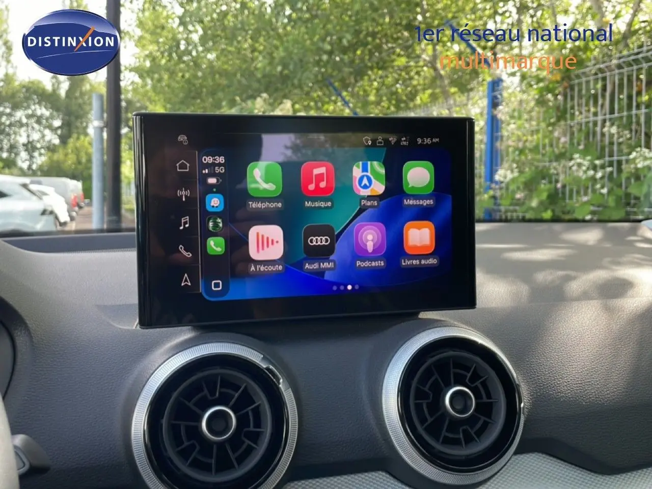 Écran tactile central de l’Audi Q2 30 TDI S-Line 2025, avec commandes multimédia et aérateurs ronds sur tableau de bord noir.