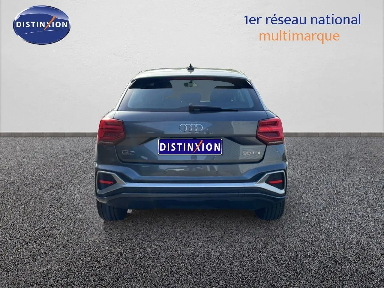 Vue arrière d'un Audi Q2 gris Manhattan métal 2025 avec feux LED et logo distinctif sur fond neutre.
