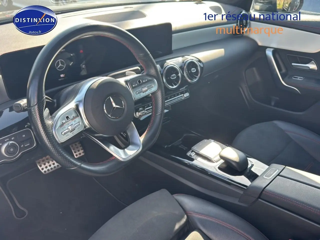 Vue intérieure côté conducteur de la Mercedes Classe CLA 250 e AMG Line 2022 avec volant cuir et finitions noires et rouges.