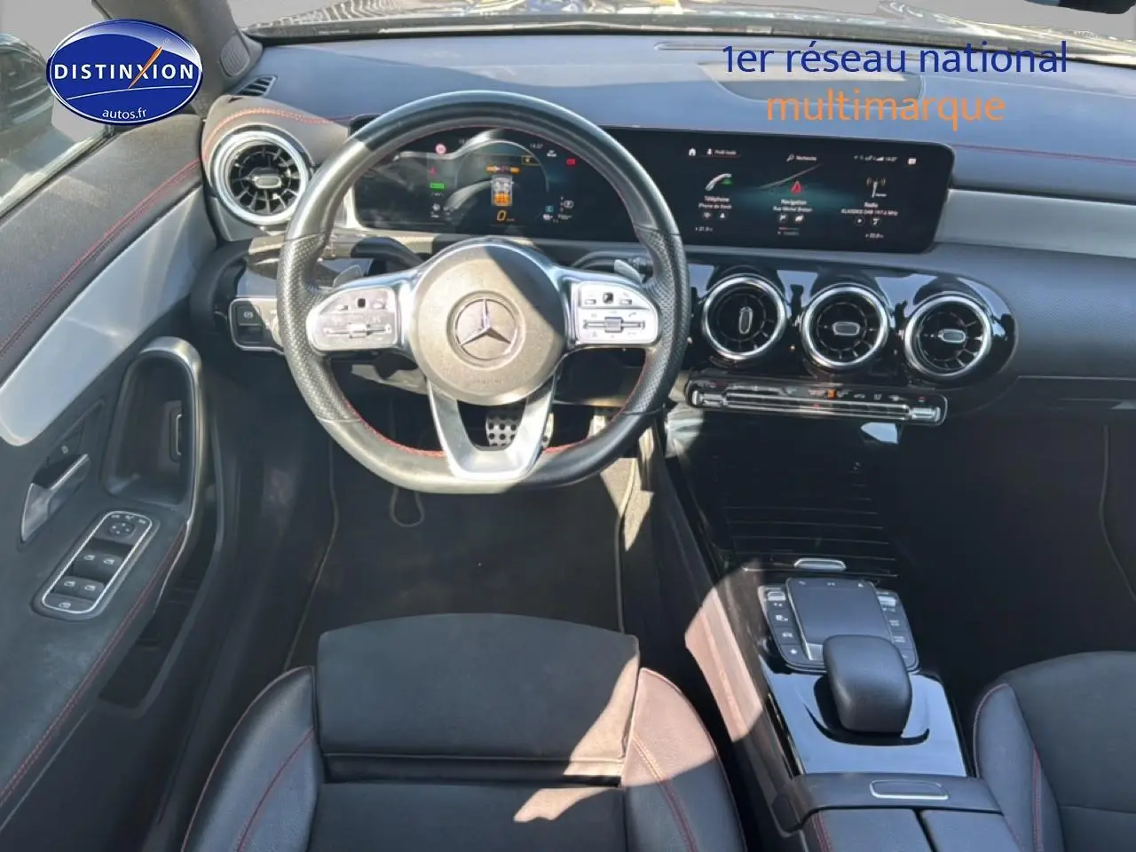 Vue intérieure avant de la Mercedes Classe CLA 250 e AMG Line 2022, volant cuir noir avec surpiqûres rouges et tableau de bord digital.