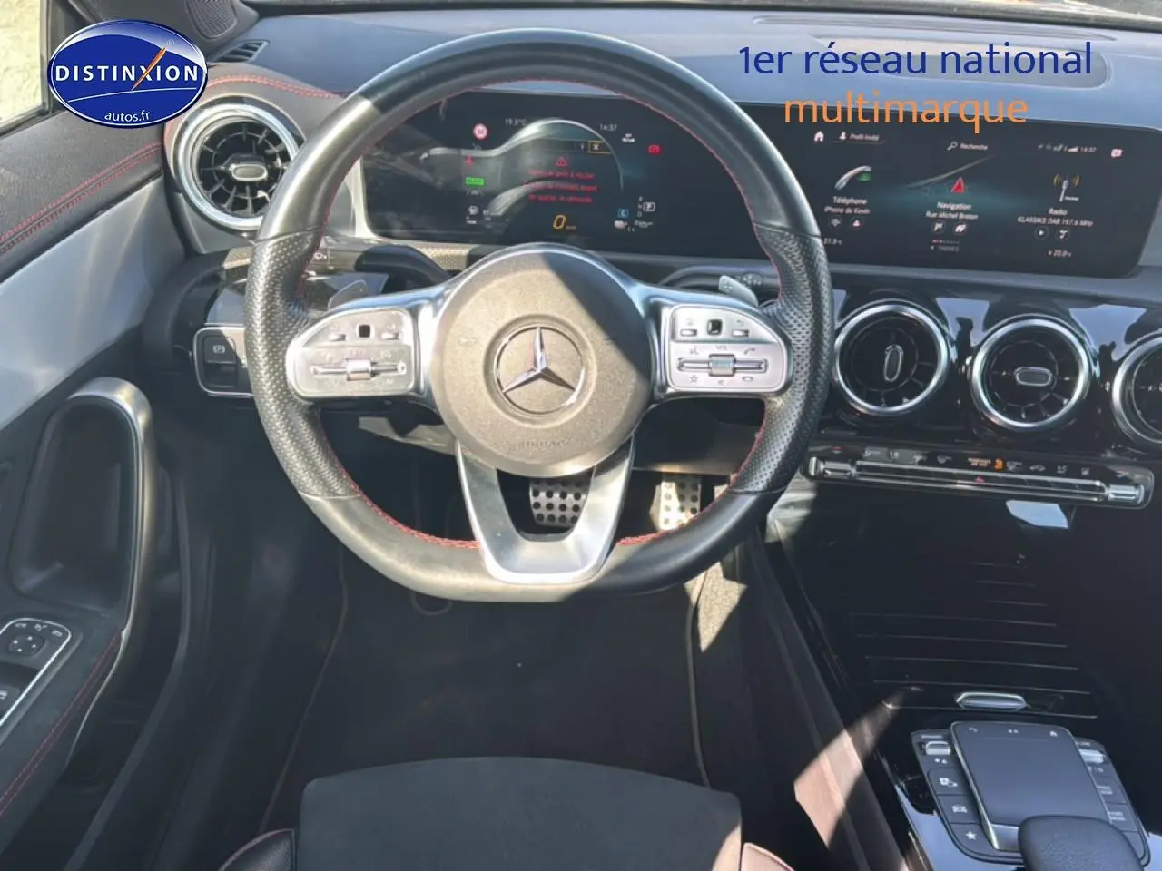 Vue intérieure centrée sur le volant cuir sport noir avec surpiqûres rouges de la Mercedes CLA 250 e AMG Line 2022.