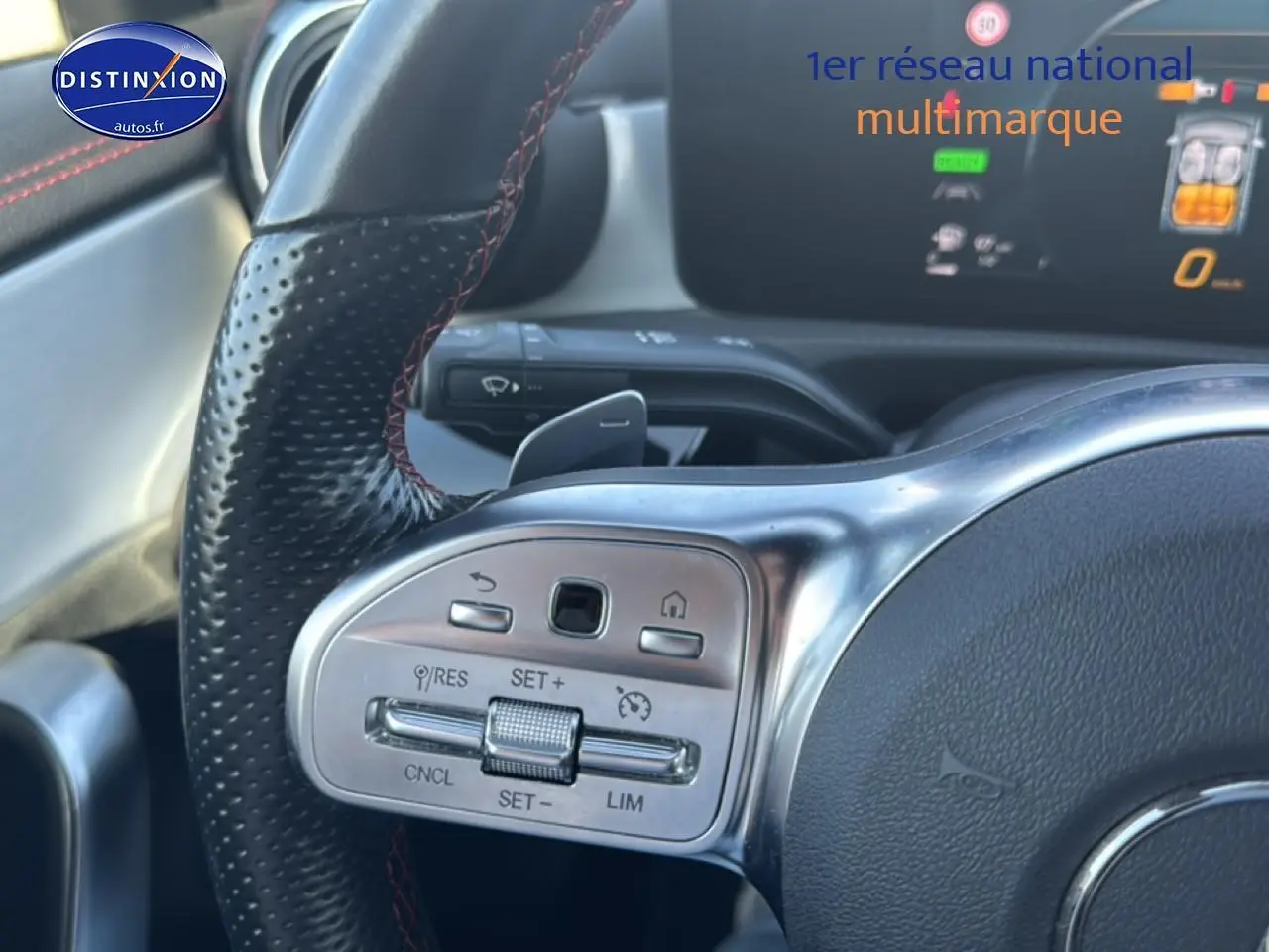 Gros plan sur le volant cuir noir avec surpiqûres rouges et commandes multifonctions d'une Mercedes Classe CLA 250 e AMG 2022.