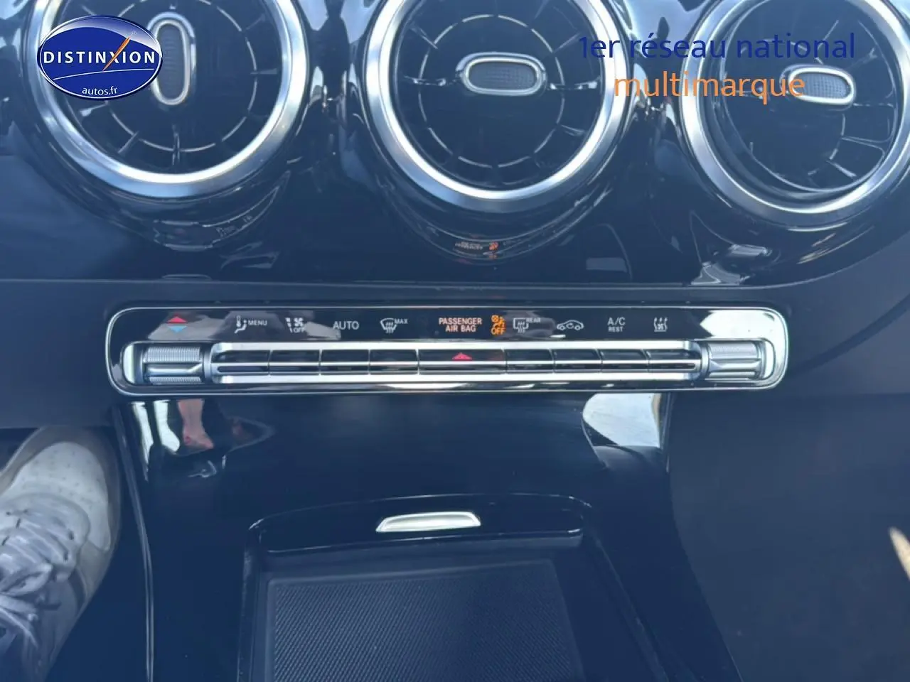 Vue rapprochée de la console centrale noire de la Mercedes Classe CLA 250 e AMG Line avec aérateurs ronds et commandes climatisation.