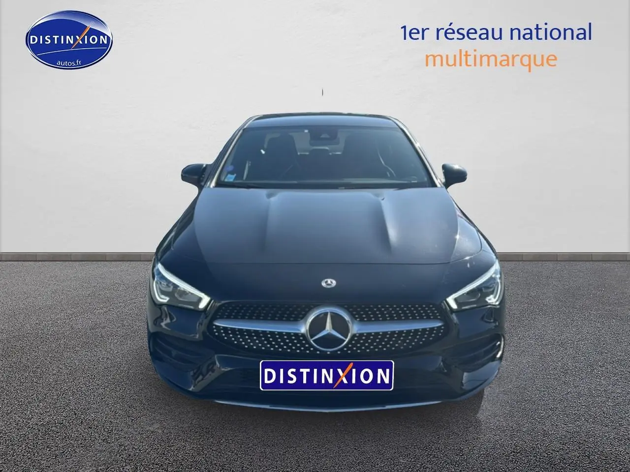 Vue frontale d'une Mercedes Classe CLA 250 e AMG Line noire avec calandre chromée et feux LED allumés.