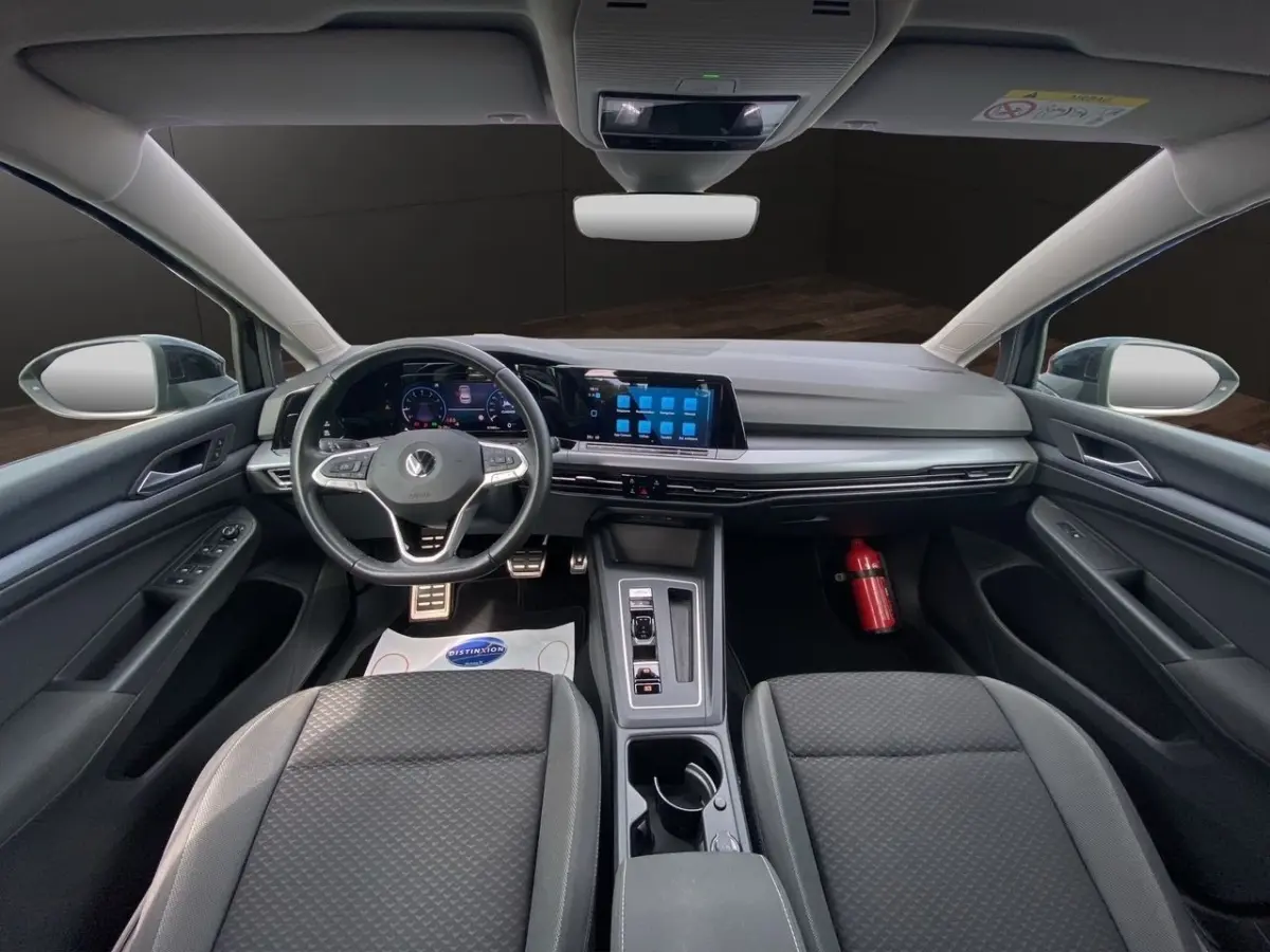 Vue intérieure avant de la Volkswagen Golf noire 2022, tableau de bord moderne avec écran tactile et volant cuir multifonctions.