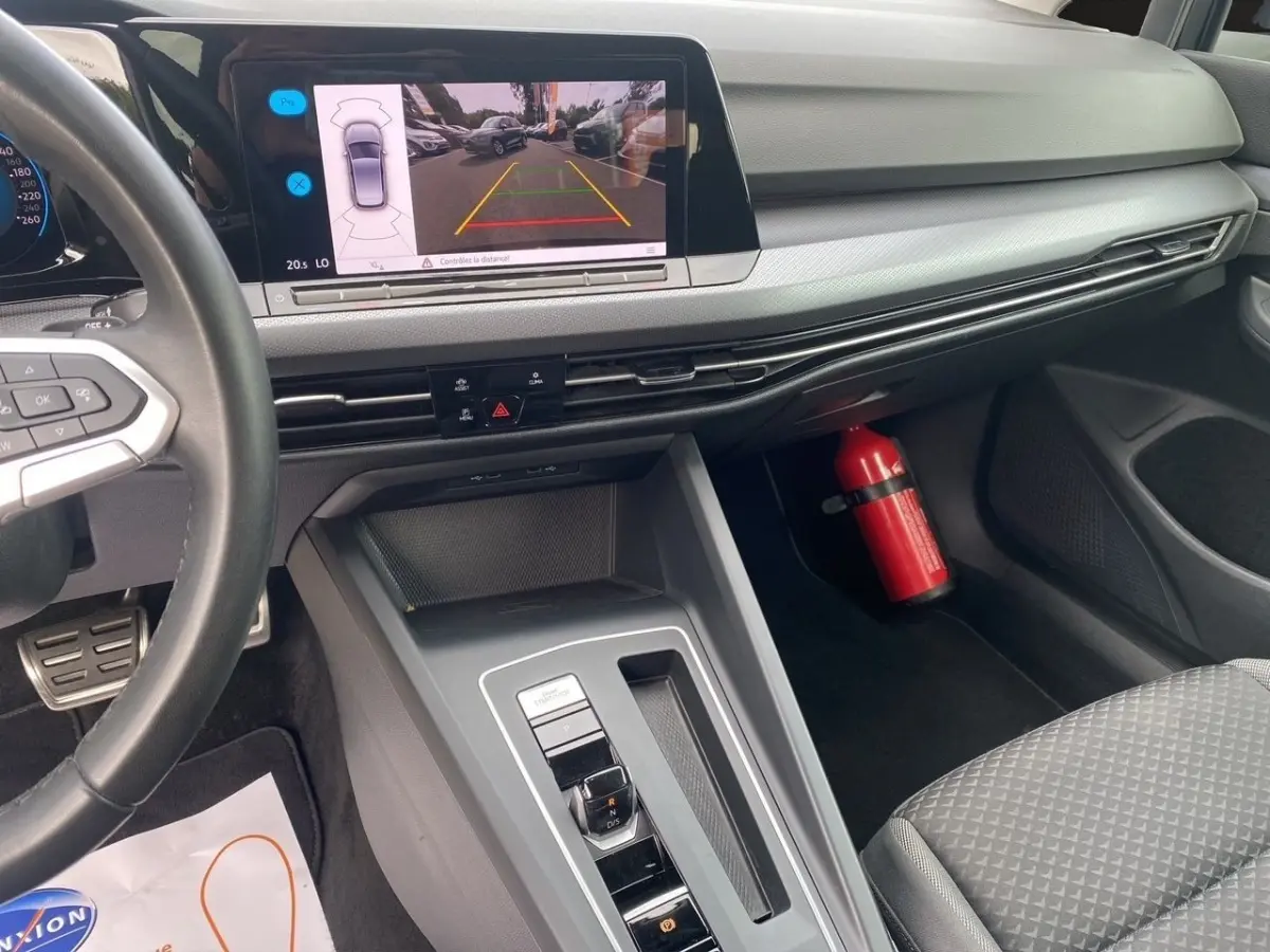 Vue intérieure côté passager avant de la Volkswagen Golf noire 2022, écran de caméra de recul et tableau de bord moderne.