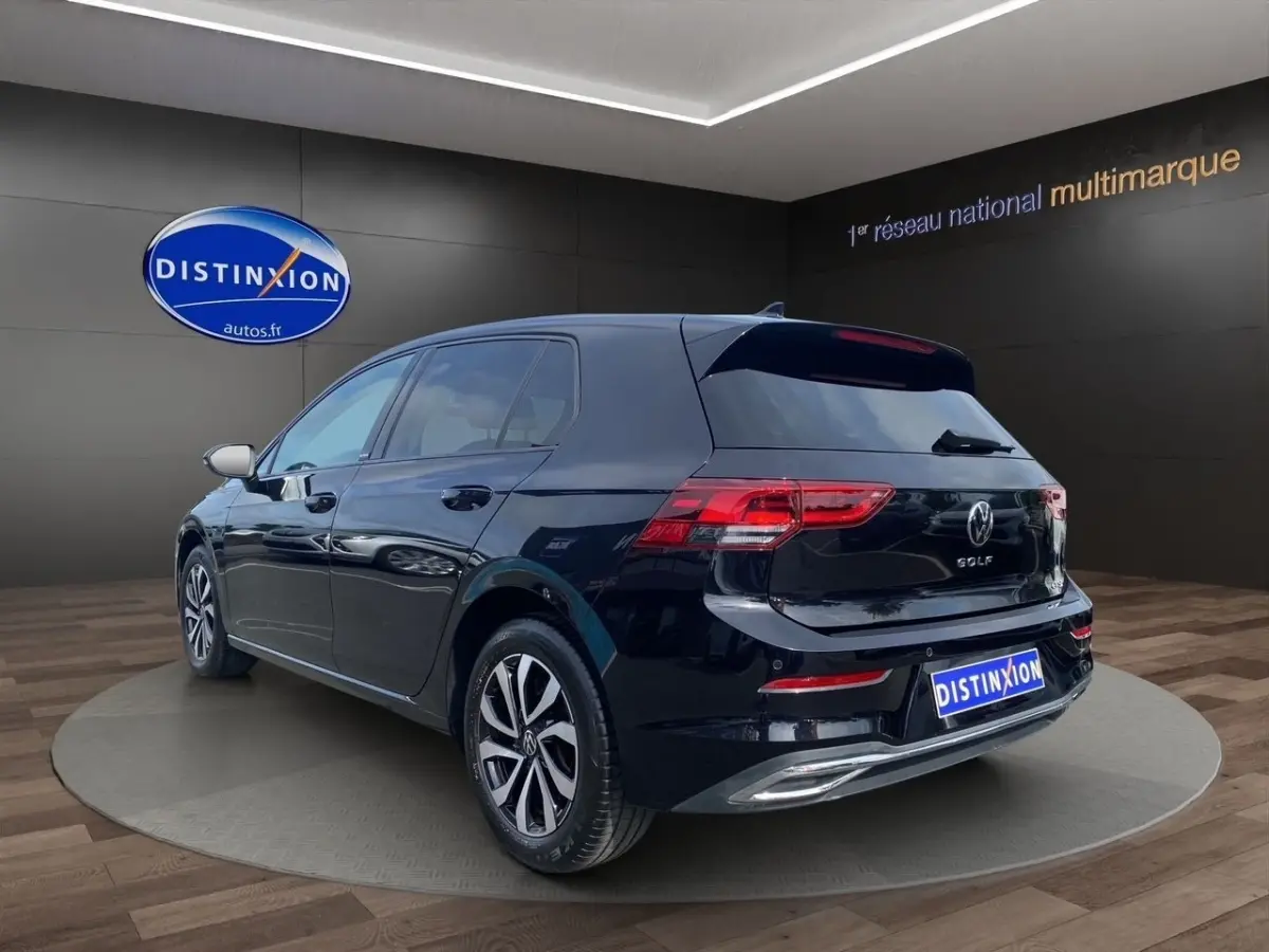 Volkswagen Golf noire vue en 3/4 arrière droit, avec vitres surteintées et feux arrière LED visibles.