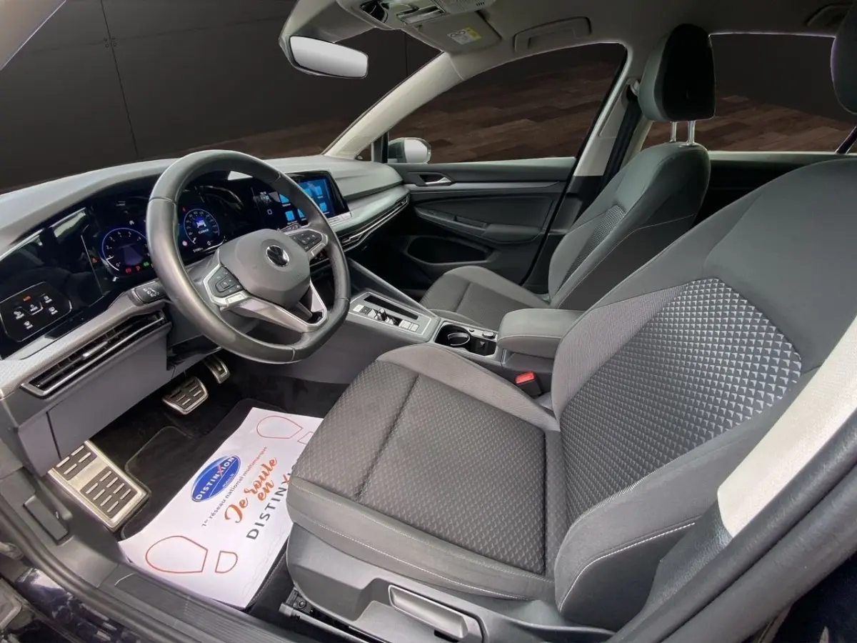 Vue intérieure côté conducteur de la Volkswagen Golf noire 2022, montrant le volant cuir et l’écran tactile central.