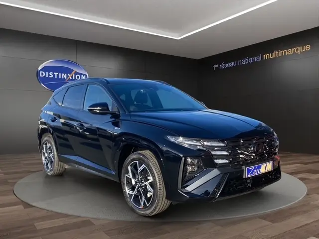 Vue 3/4 avant d’un Hyundai Tucson noir 2026 N Line Creative avec jantes alliage et hayon motorisé en showroom.