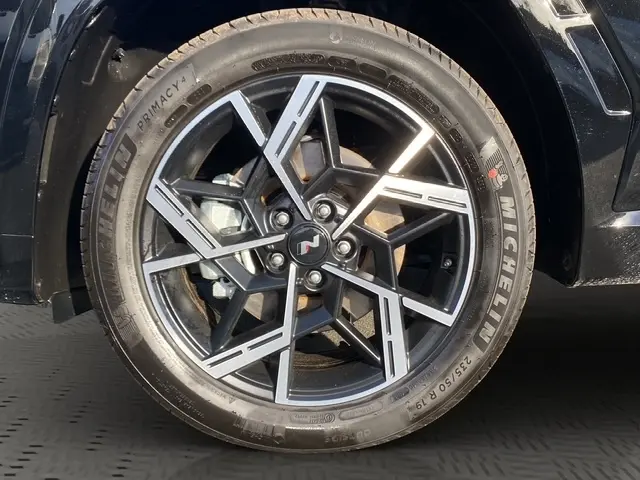 Gros plan sur la roue avant droite noire du Hyundai Tucson 1.6 Hybrid N Line avec jante alliage au design géométrique.