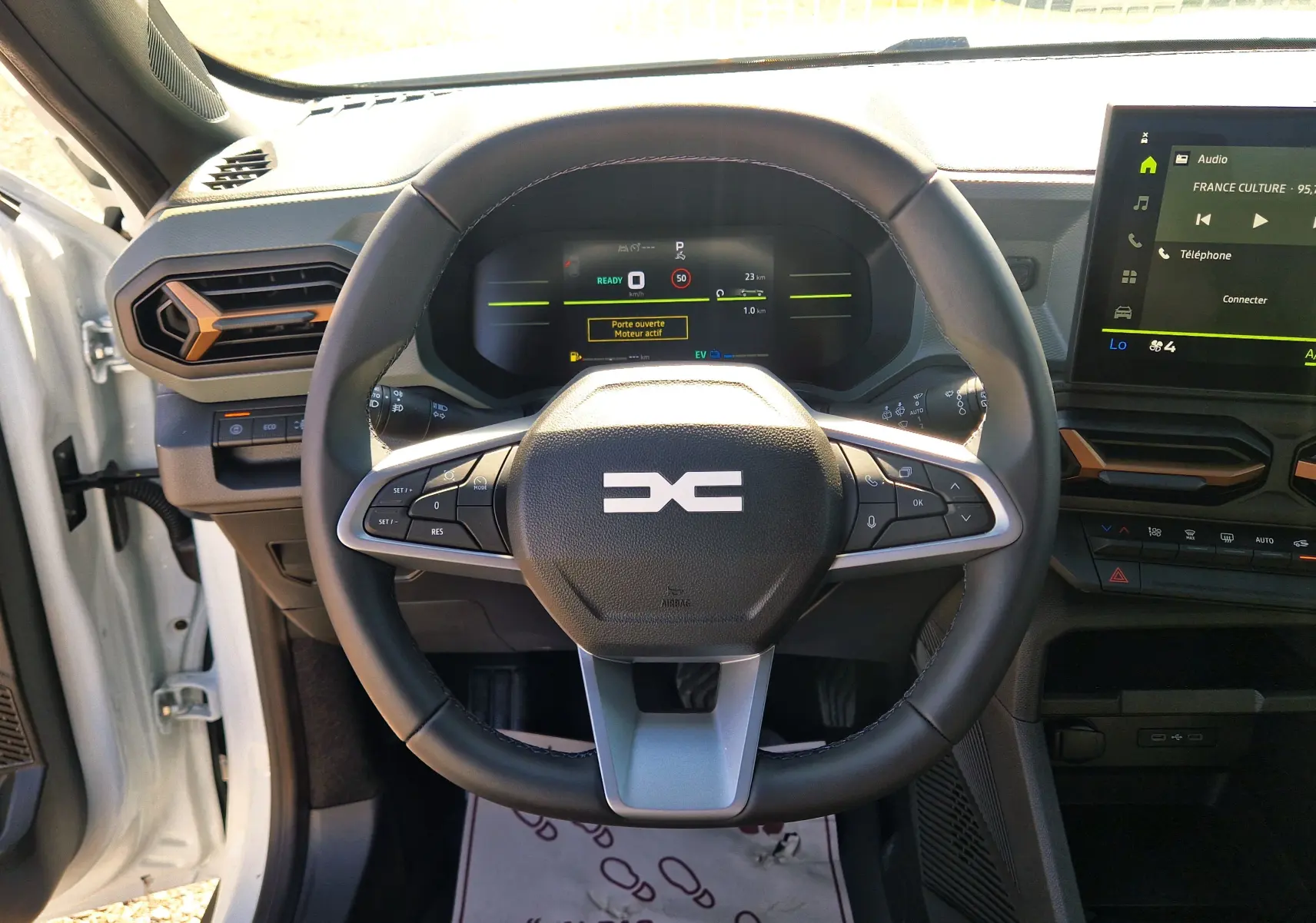 Vue intérieure centrée sur le volant du Dacia Duster blanc 2026, avec tableau de bord numérique et écran tactile visible.