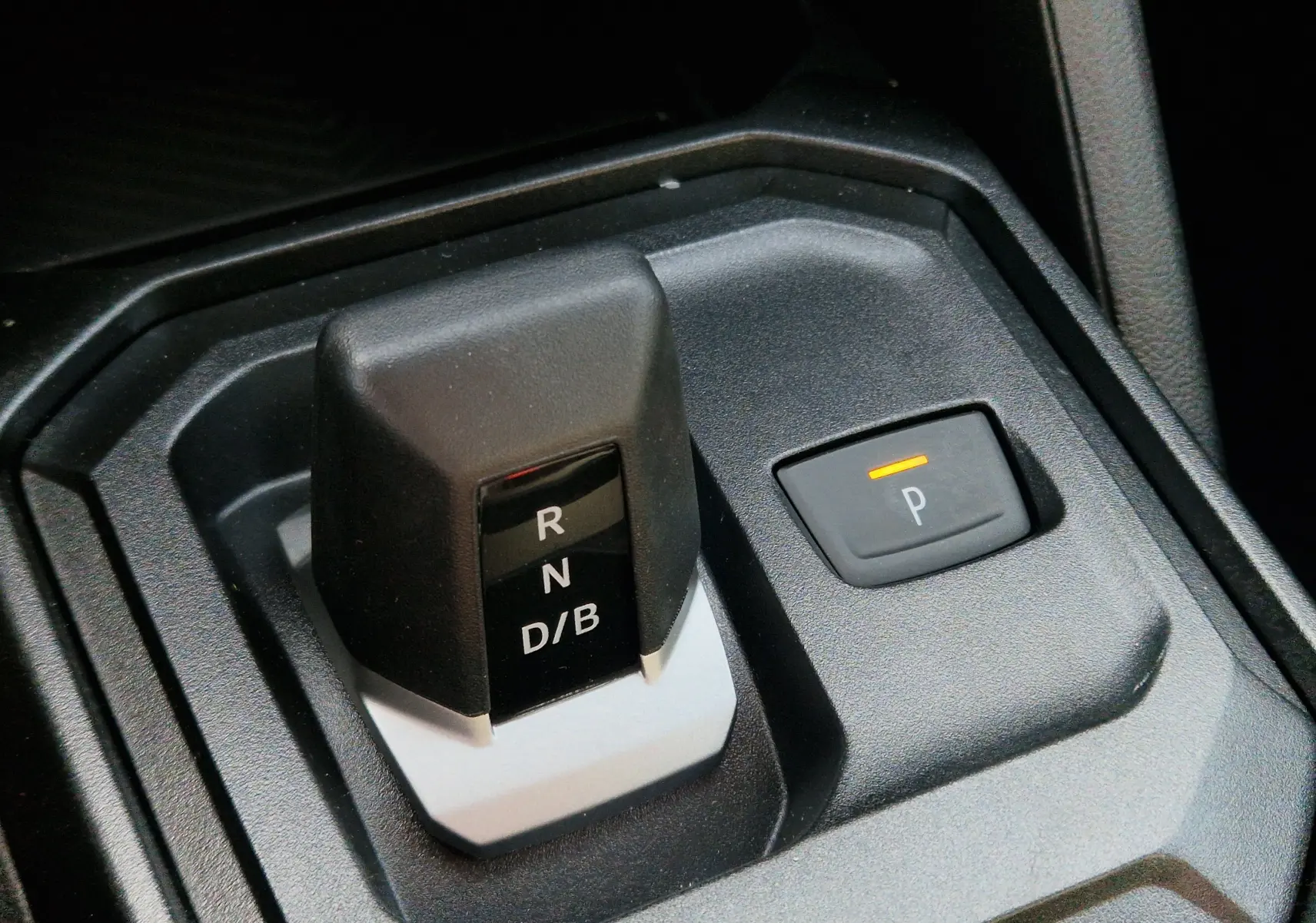 Gros plan sur le levier de vitesses automatique noir et gris avec bouton de parking éclairé dans un Dacia Duster blanc 2026.