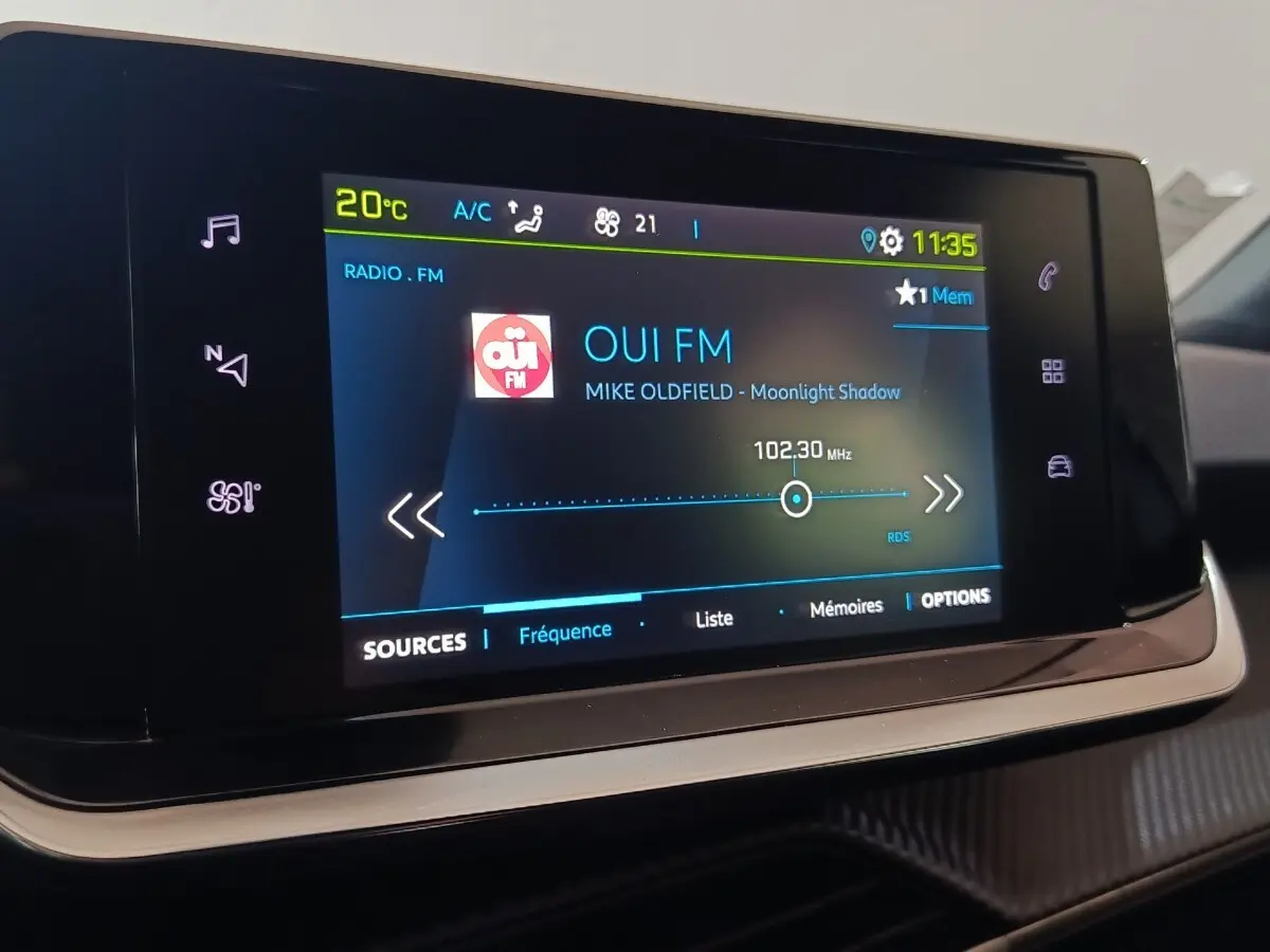 Écran tactile central du tableau de bord de la Peugeot E-2008 électrique, affichant la radio FM.