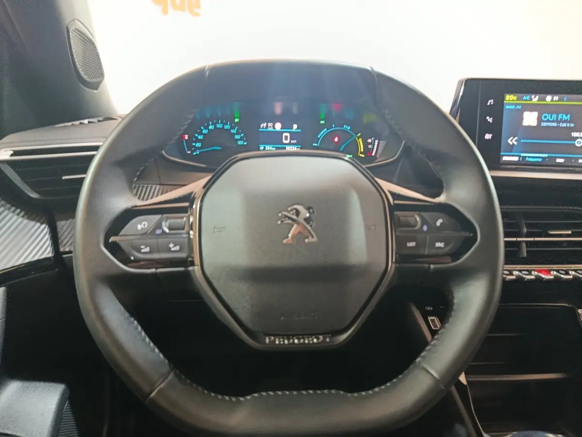 Vue intérieure centrée sur le volant cuir multifonctions et le combiné numérique du Peugeot E-2008 électrique 2023.
