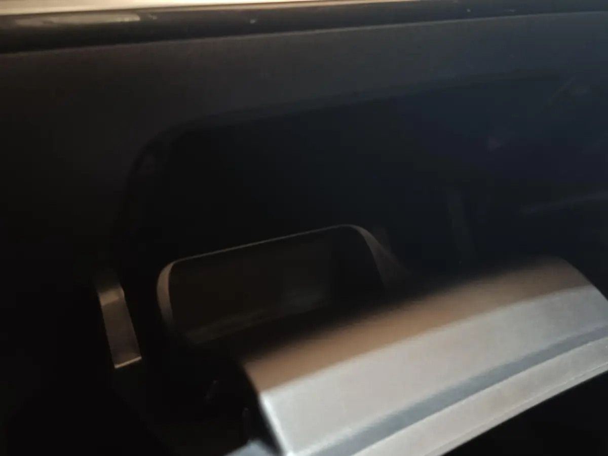 Gros plan sur la boîte à gants réfrigérée ouverte du Peugeot E-2008 électrique gris clair, intérieur sombre.
