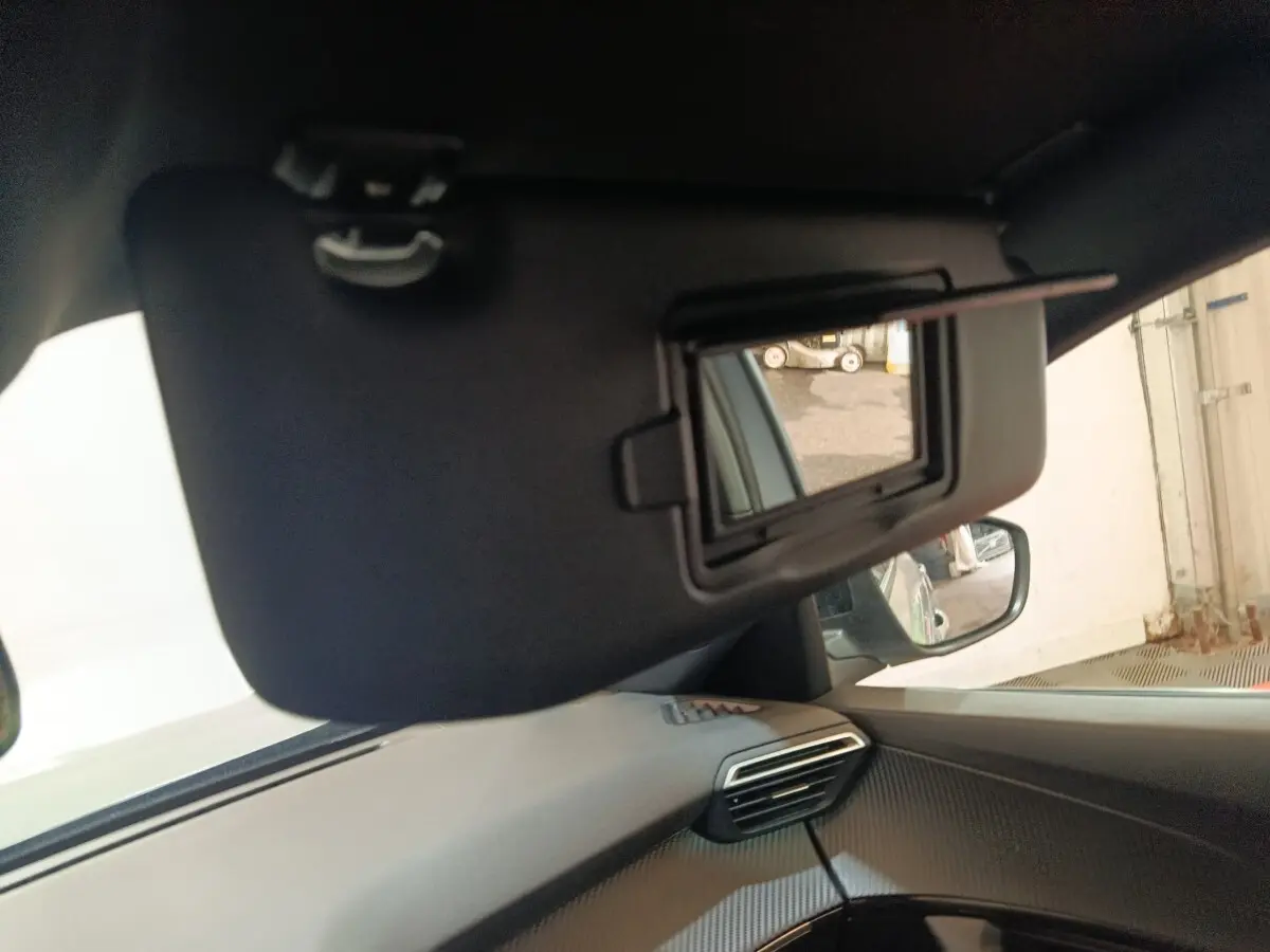 Détail intérieur montrant le pare-soleil avec miroir ouvert côté conducteur du Peugeot E-2008 électrique gris clair 2023.