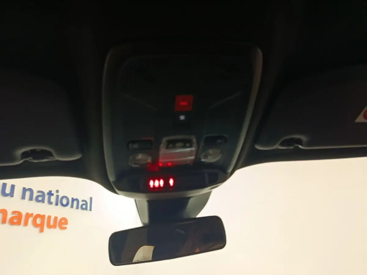 Vue intérieure du plafond avant de la Peugeot E-2008 électrique 2023, avec éclairage et commandes au-dessus du rétroviseur central.