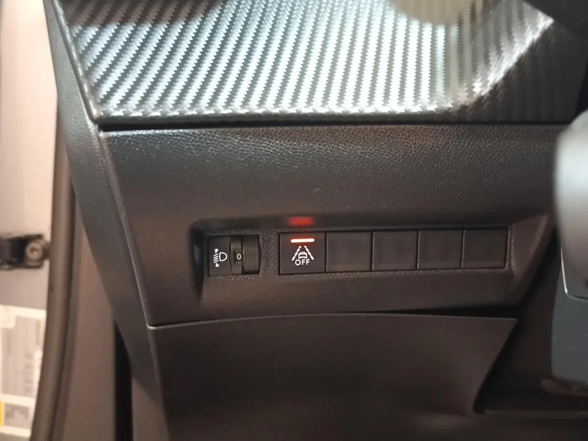 Détail du tableau de bord côté gauche avec bouton d'assistance à la conduite activé sur Peugeot E-2008 gris clair électrique.