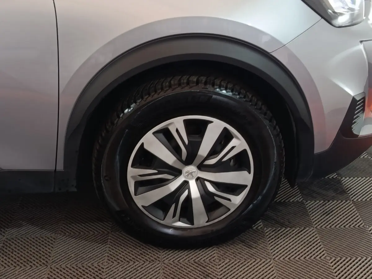 Gros plan sur la roue avant droite d’un Peugeot E-2008 électrique gris clair avec jante au design moderne.