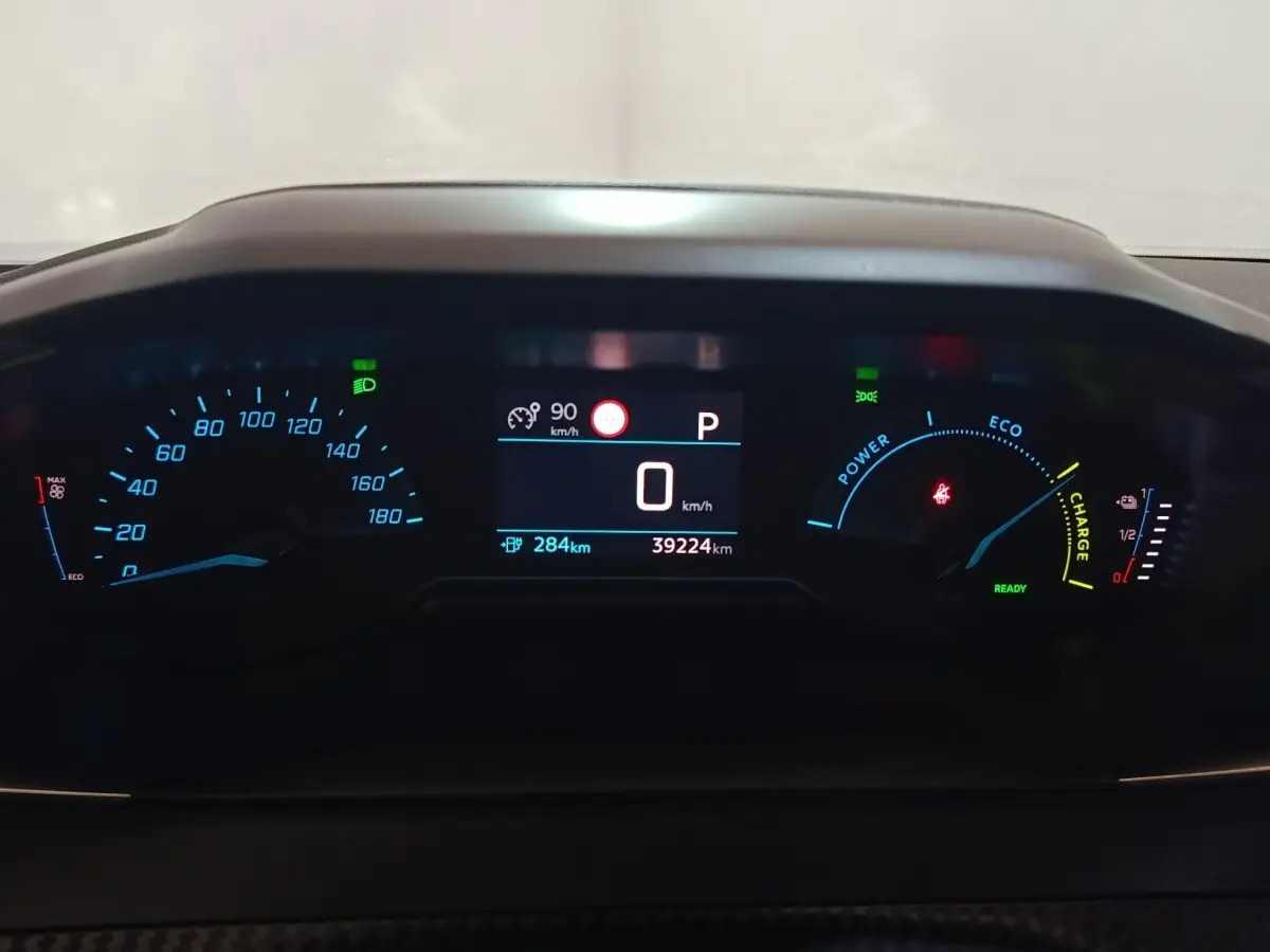 Gros plan sur le combiné d'instruments numérique du Peugeot E-2008 électrique, affichage vitesse et autonomie.