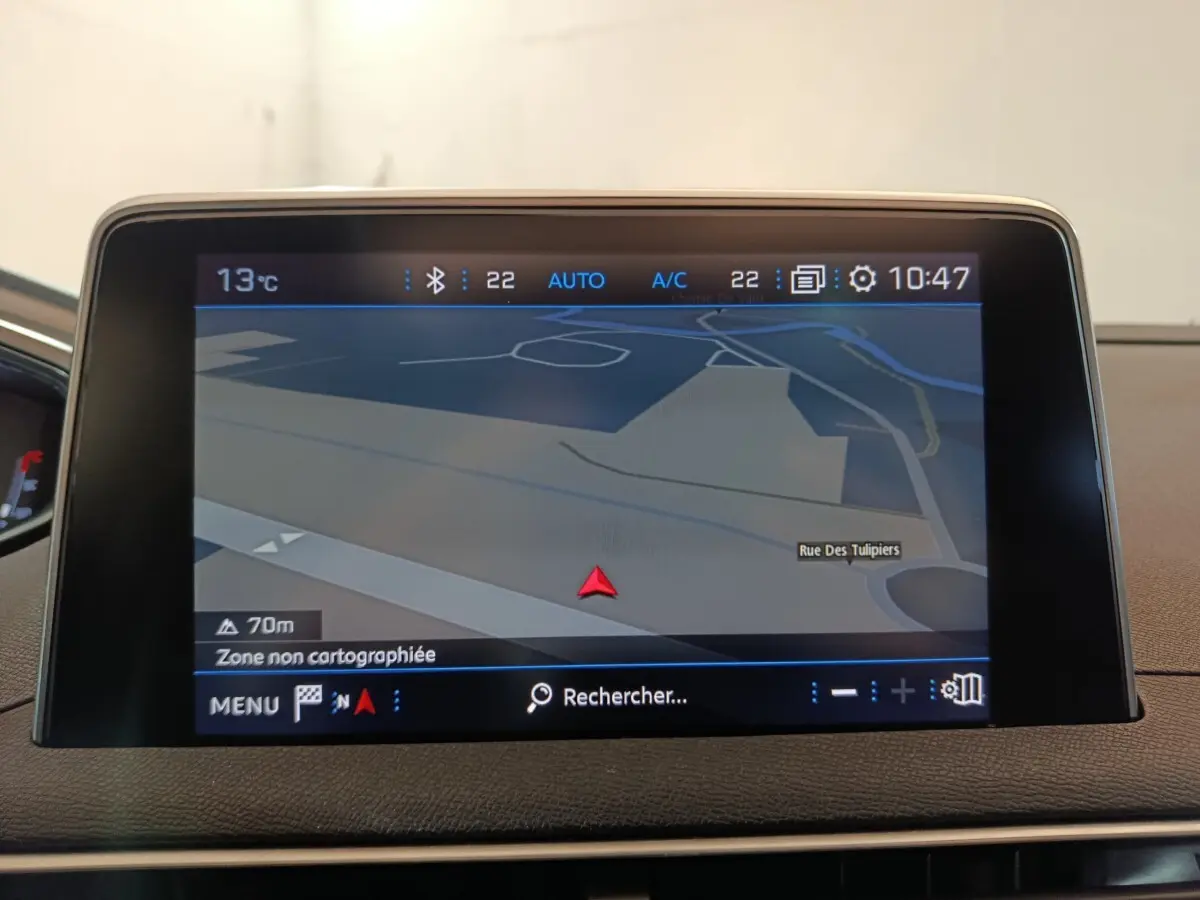 Écran tactile central du tableau de bord du Peugeot 3008 blanc, affichant la navigation GPS en mode 3D.